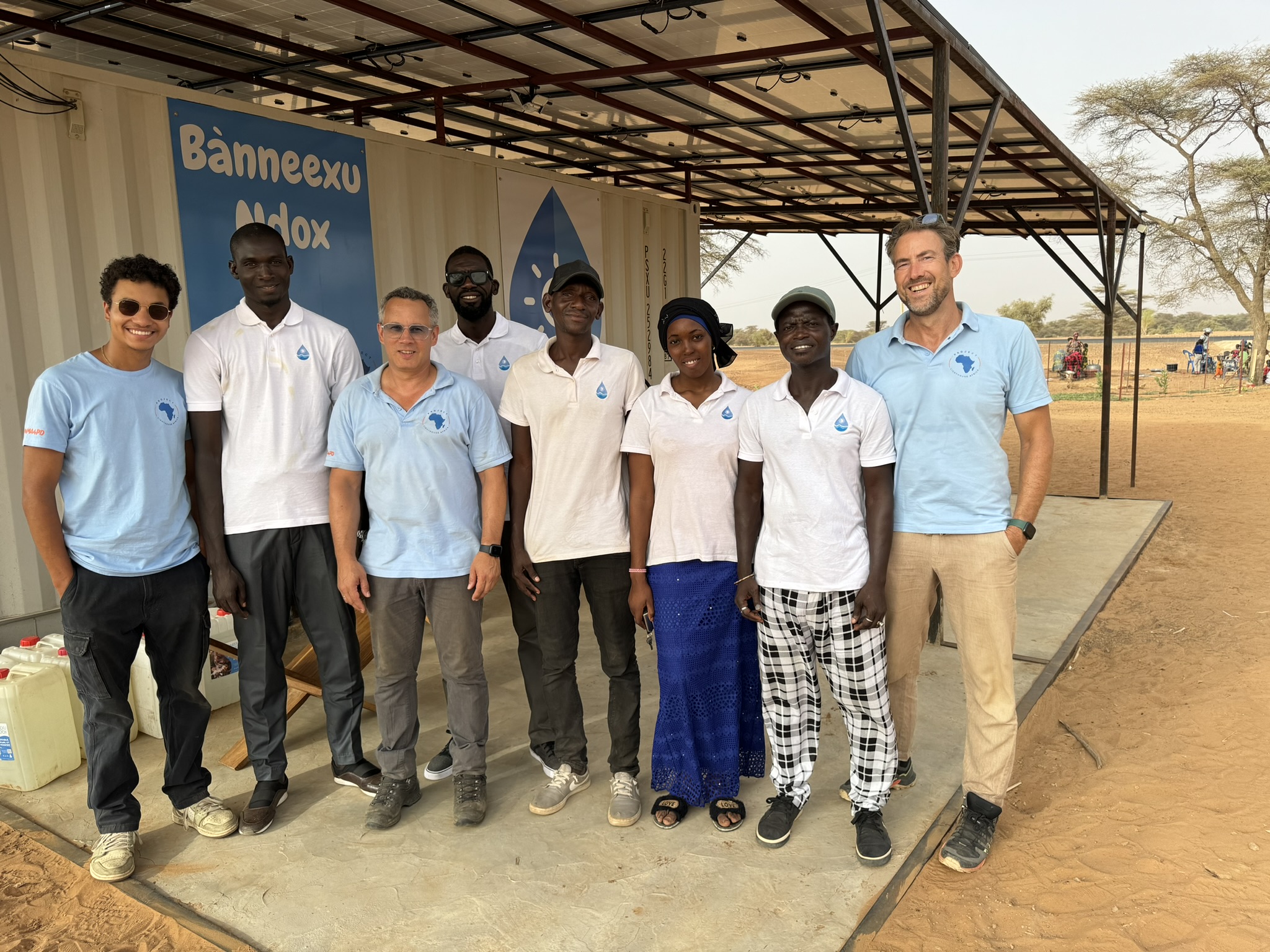 Group of Project Lighthouse Africa members and local partner company in front of a Senegalese water kiosk